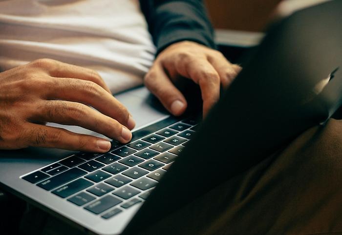 Händer som skriver på tangentbord på laptop