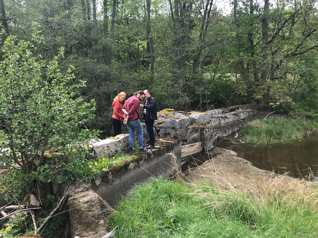 Foto på tre personer som inspekterar dammen